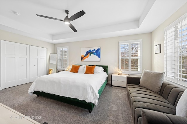 bedroom with ceiling fan, carpet floors, and a raised ceiling