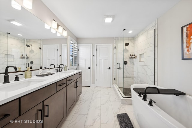 bathroom featuring marble finish floor, a freestanding tub, a sink, and a shower stall