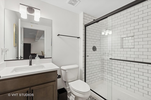 bathroom featuring toilet, a stall shower, visible vents, and vanity