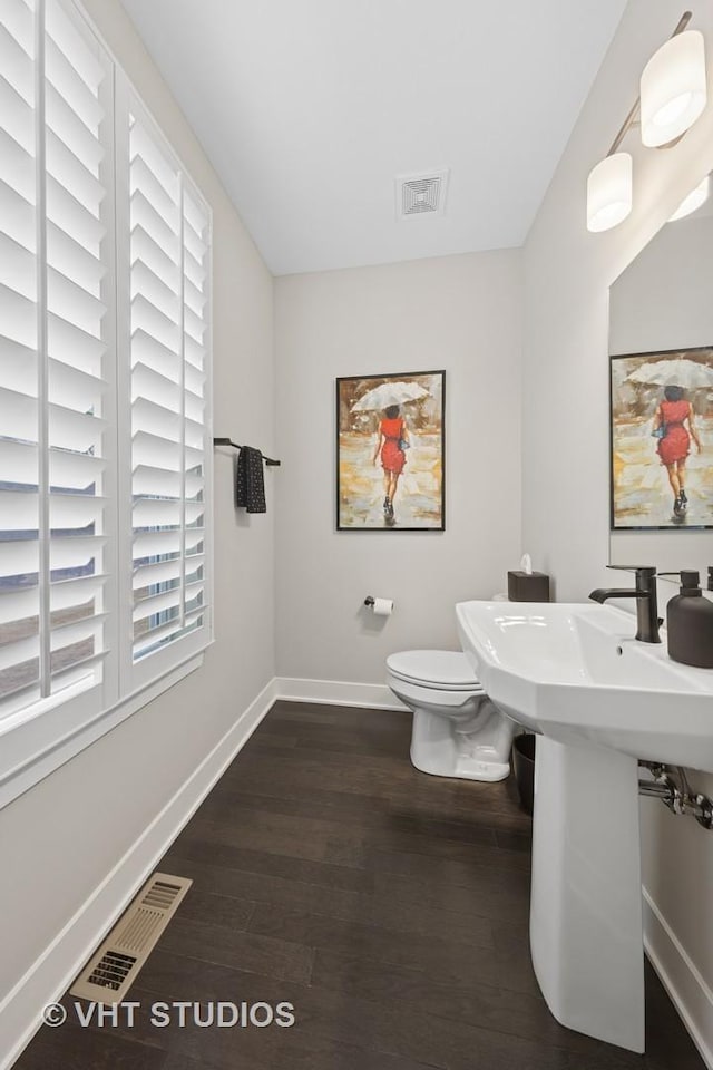 bathroom with toilet, baseboards, visible vents, and wood finished floors