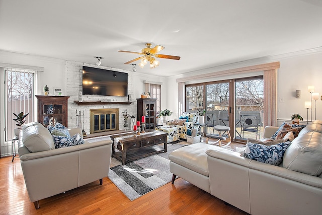 living room with a brick fireplace, crown molding, and hardwood / wood-style floors