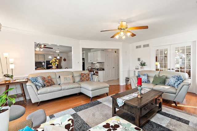 living room featuring french doors, ceiling fan, ornamental molding, and light wood-type flooring