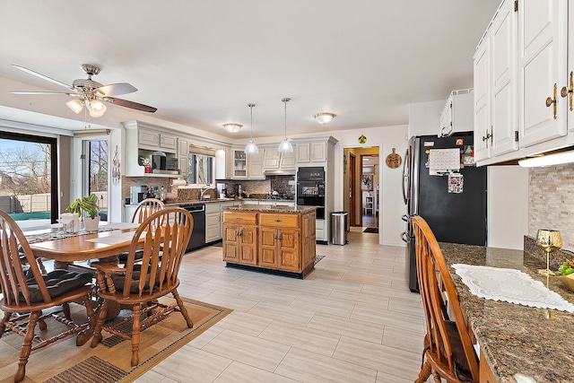 kitchen featuring pendant lighting, white cabinetry, dark stone countertops, tasteful backsplash, and black appliances