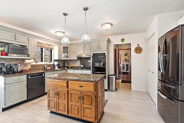 kitchen featuring sink, a center island, dark stone countertops, pendant lighting, and stainless steel appliances