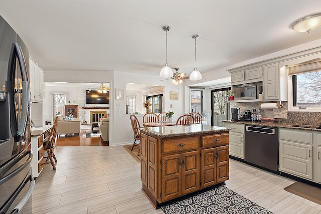 kitchen with a kitchen island, appliances with stainless steel finishes, a fireplace, decorative light fixtures, and backsplash