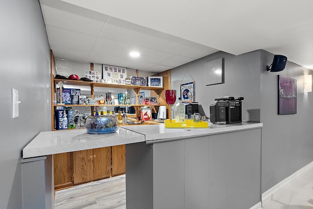 bar featuring a drop ceiling and light hardwood / wood-style flooring