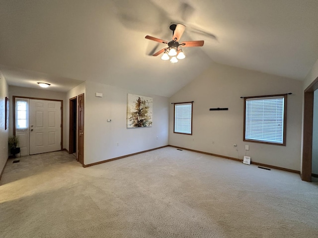 unfurnished living room with light carpet, a wealth of natural light, vaulted ceiling, and ceiling fan