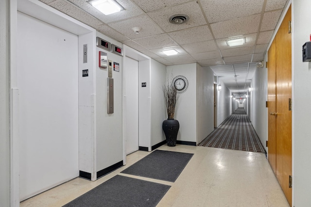 hall featuring a drop ceiling and elevator