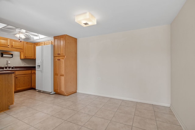 kitchen with sink, light tile patterned floors, white refrigerator with ice dispenser, and ceiling fan