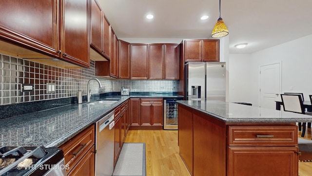 kitchen with a center island, dark stone countertops, pendant lighting, stainless steel appliances, and beverage cooler