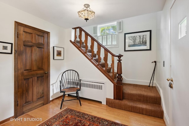 stairs featuring radiator heating unit and hardwood / wood-style floors