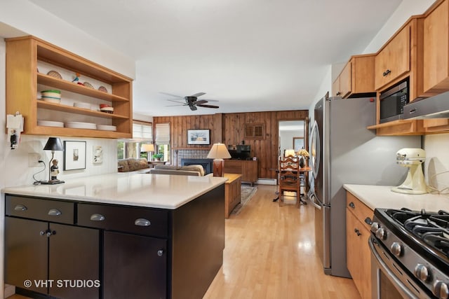 kitchen with ceiling fan, wooden walls, gas range, kitchen peninsula, and light wood-type flooring