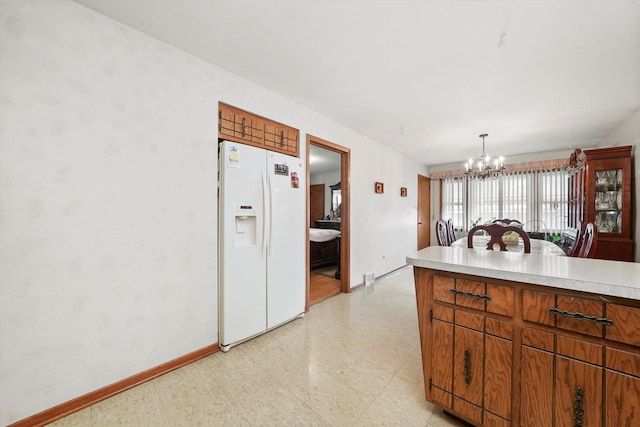 kitchen with white fridge with ice dispenser, a notable chandelier, and decorative light fixtures