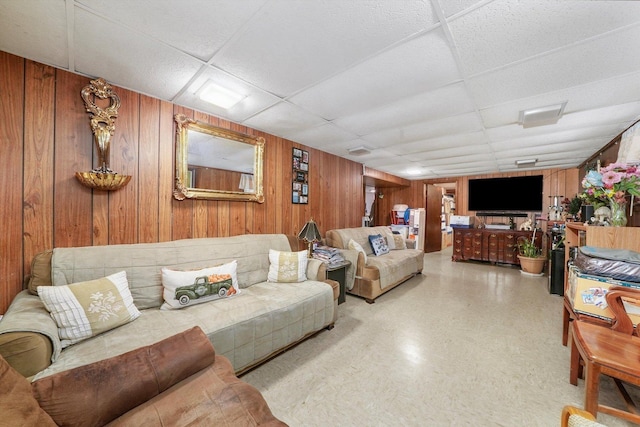 living room featuring a drop ceiling and wooden walls