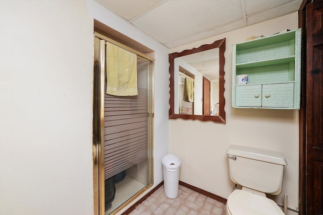 bathroom featuring a drop ceiling, an enclosed shower, and toilet