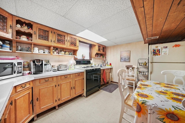 kitchen with gas range, a paneled ceiling, and white fridge