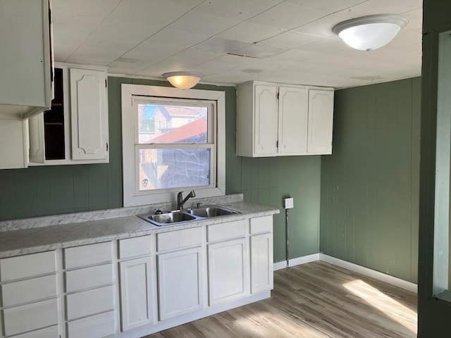 kitchen with white cabinetry, sink, and light hardwood / wood-style flooring