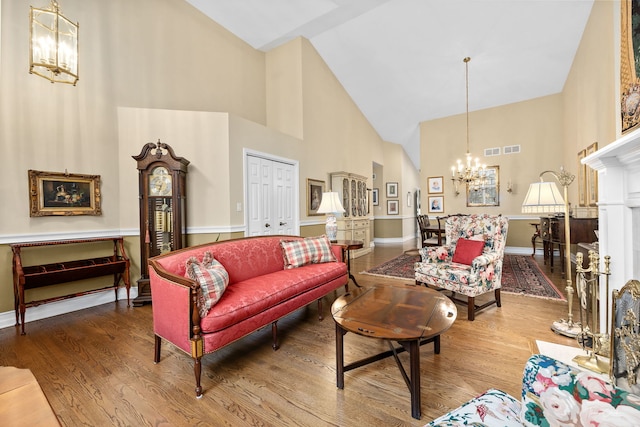 living room with wood-type flooring, a chandelier, and high vaulted ceiling