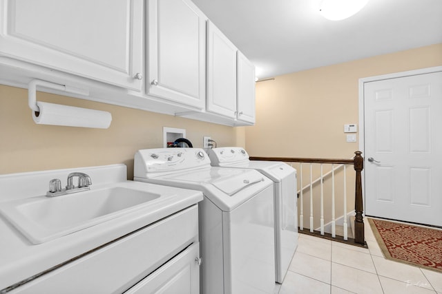 washroom featuring light tile patterned floors, sink, washing machine and dryer, and cabinets