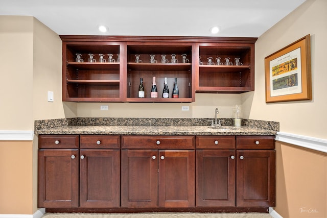 bar featuring sink and dark stone countertops