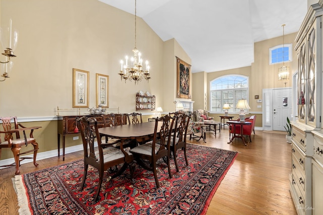 dining room featuring an inviting chandelier, high vaulted ceiling, and light wood-type flooring