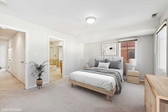 bedroom with connected bathroom and light colored carpet