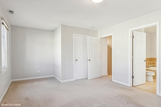 unfurnished bedroom with light carpet, connected bathroom, and a closet