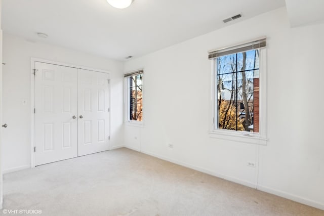 unfurnished bedroom with light colored carpet and a closet