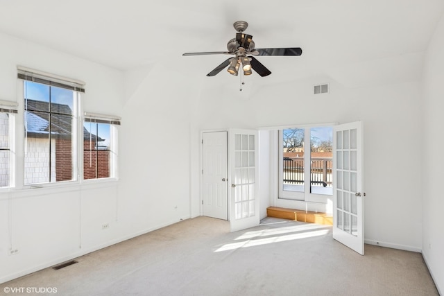 empty room featuring french doors, ceiling fan, and light carpet