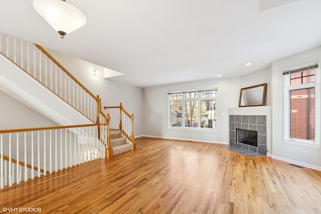 unfurnished living room with a tiled fireplace and light hardwood / wood-style flooring