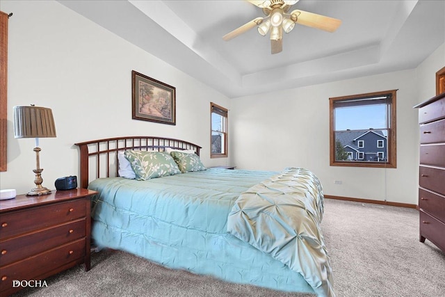 carpeted bedroom featuring ceiling fan and a tray ceiling