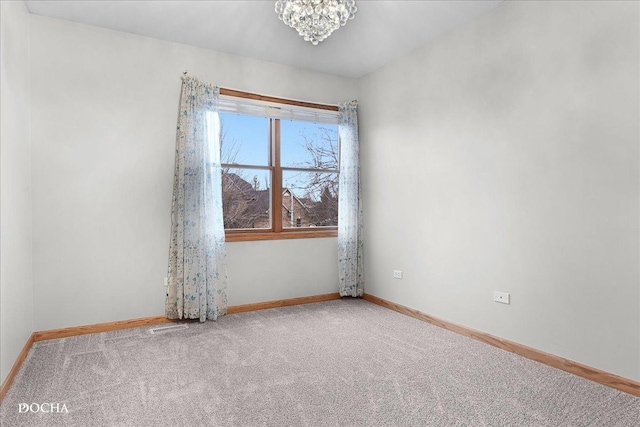 carpeted empty room with a notable chandelier