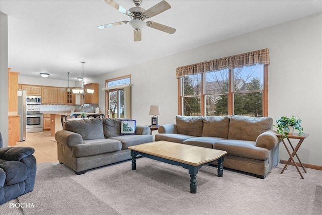 carpeted living room featuring ceiling fan with notable chandelier