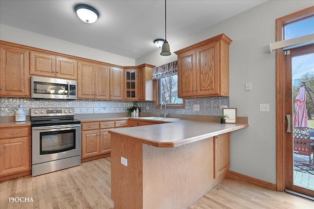 kitchen featuring sink, backsplash, light hardwood / wood-style floors, kitchen peninsula, and stainless steel appliances