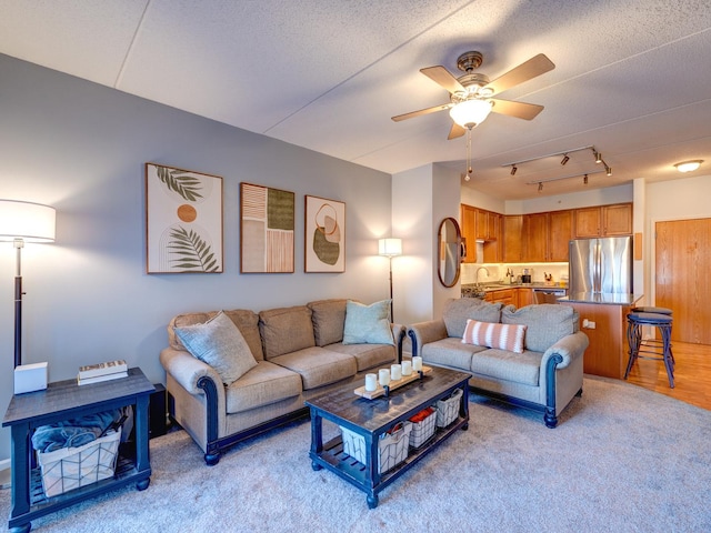 living room featuring a ceiling fan, rail lighting, light wood-style floors, and a textured ceiling