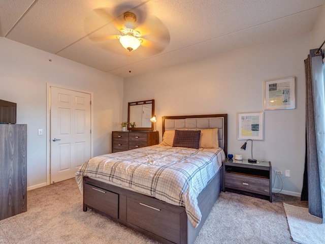 bedroom with light carpet, a textured ceiling, baseboards, and a ceiling fan