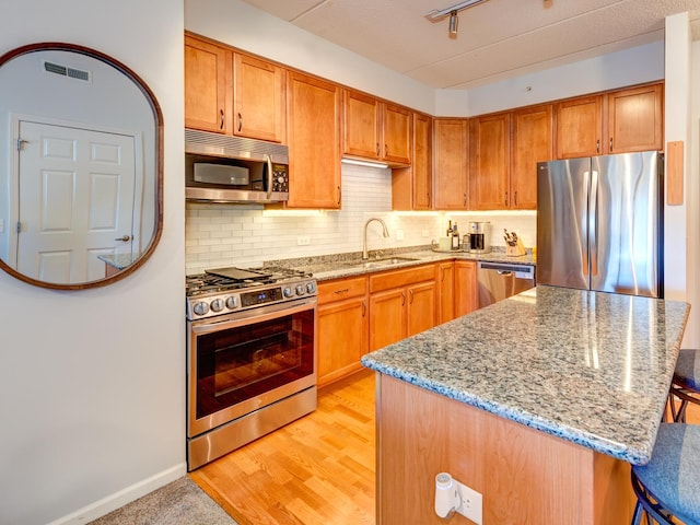 kitchen featuring tasteful backsplash, visible vents, a breakfast bar, stainless steel appliances, and a sink