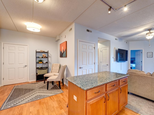 kitchen with light wood finished floors, visible vents, open floor plan, and a center island