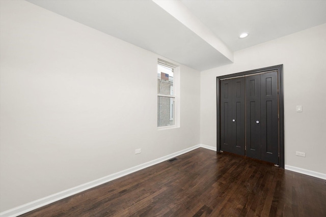 unfurnished bedroom with a closet and dark hardwood / wood-style floors