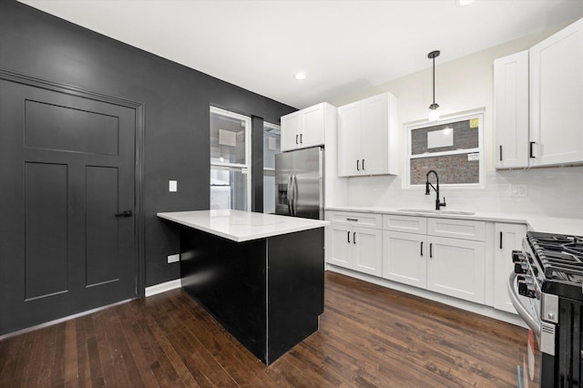 kitchen with sink, white cabinetry, decorative light fixtures, dark hardwood / wood-style floors, and stainless steel appliances