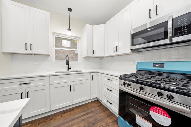 kitchen featuring appliances with stainless steel finishes, dark hardwood / wood-style floors, pendant lighting, sink, and white cabinets