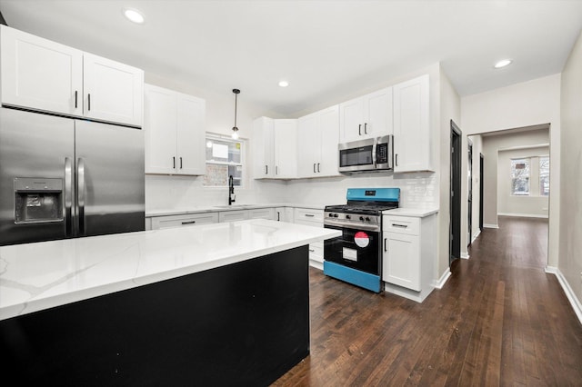 kitchen with appliances with stainless steel finishes, decorative light fixtures, sink, and white cabinets