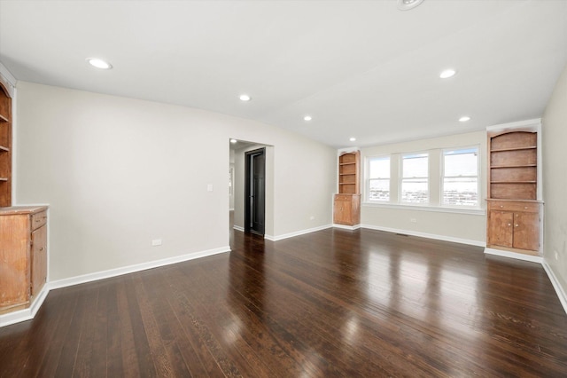 unfurnished living room with vaulted ceiling, dark hardwood / wood-style floors, and built in features