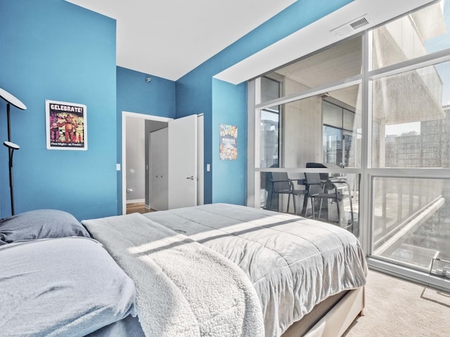 bedroom with expansive windows, carpet flooring, and multiple windows