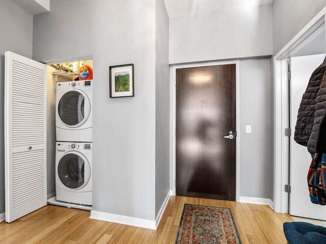 laundry room with wood-type flooring and stacked washer and clothes dryer