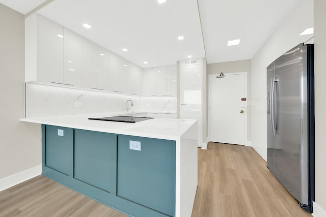 kitchen featuring stainless steel refrigerator with ice dispenser, kitchen peninsula, and white cabinets