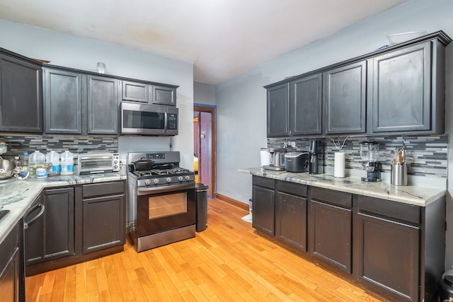 kitchen with tasteful backsplash, light wood-type flooring, and appliances with stainless steel finishes