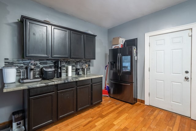 kitchen with stainless steel fridge, light wood-type flooring, and decorative backsplash