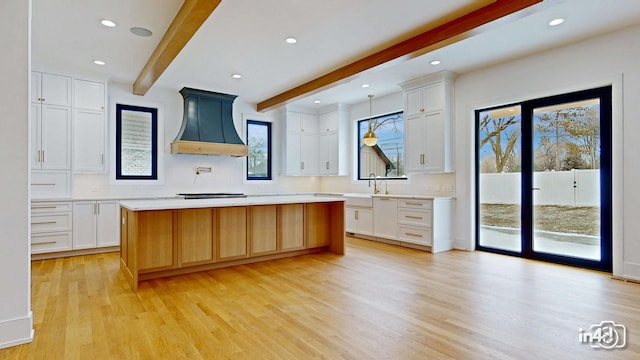 kitchen featuring white cabinetry, a kitchen island, premium range hood, and beam ceiling