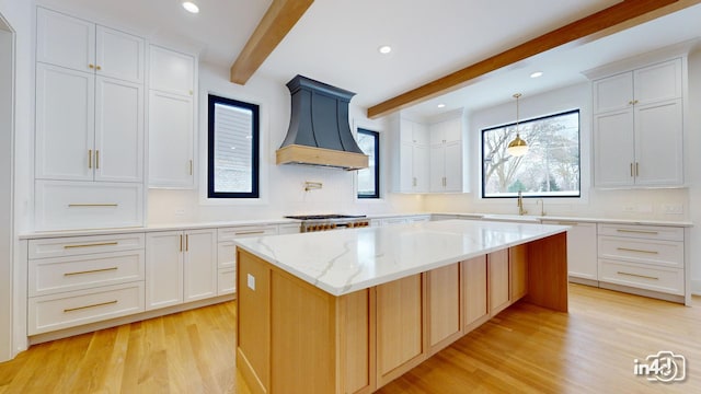 kitchen with premium range hood, a center island, and white cabinets